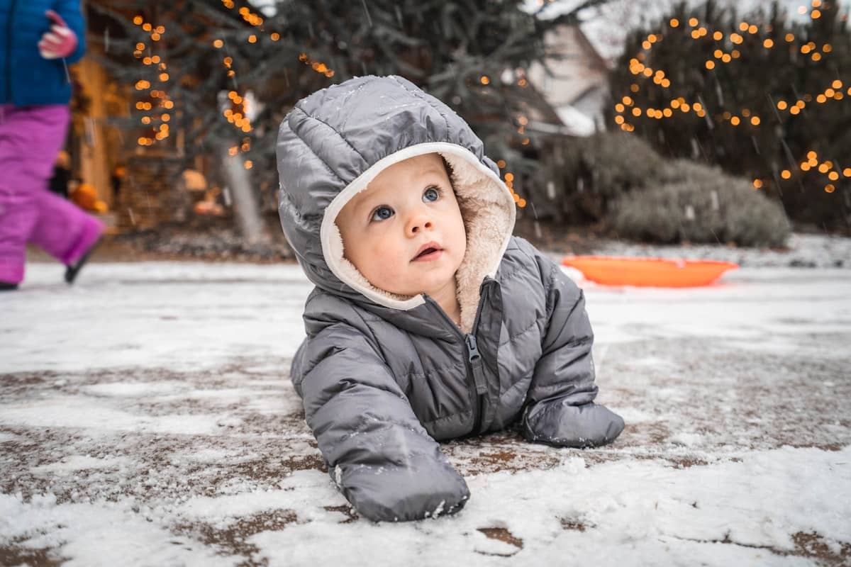 A child in a winter jacket lying in the snow